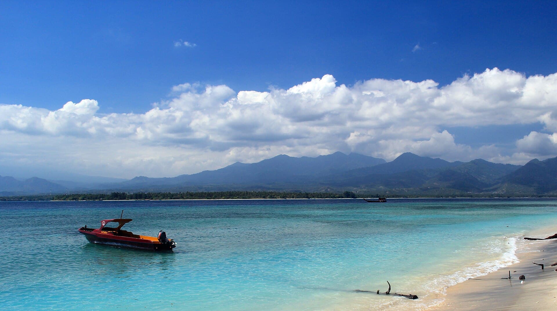 Speedboat di air toska lepas pantai timur Gili Air, dengan pegunungan Lombok di latar belakang